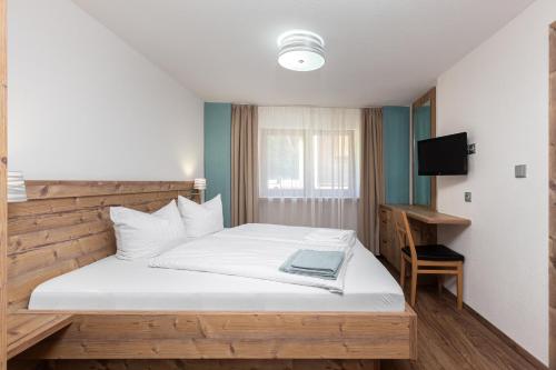 a bedroom with a bed and a desk and a television at Garni Stefani in Vent