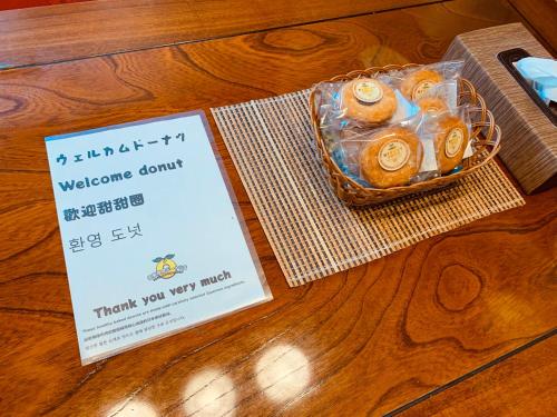 a welcome donut in a plastic container on a table with a sign at Condominium WAFU TEI Okinawa city in Okinawa City