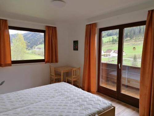 a bedroom with a bed and two large windows at Gästehaus Gruber in Pusterwald