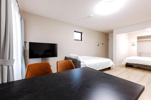 a room with a table and two beds and a tv at Anecis笠取町2 in Nagoya