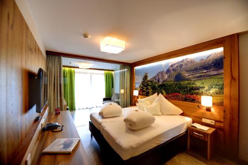 ein Hotelzimmer mit einem Bett mit einem Gemälde an der Wand in der Unterkunft Hotel Arnika in Ischgl