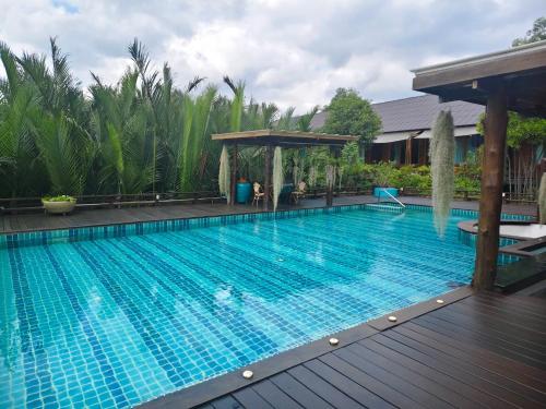 a large swimming pool with a wooden deck at Baan Krai Nao The Riverfront in Bangkok