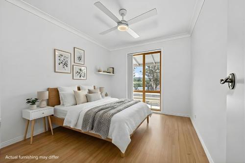 ein weißes Schlafzimmer mit Bett und Deckenventilator in der Unterkunft Sunlit on the Clyde in Nelligen