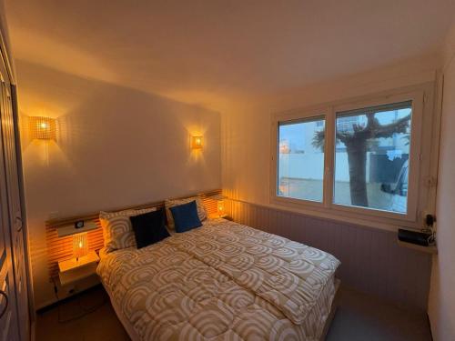 a bedroom with a bed with two lamps and a window at Strandhuisje aan de Middellandse Zee in Palavas-les-Flots