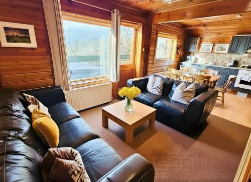 a living room with a leather couch and a table at Tor View Lodge with Hot Tub & Sauna - Spa Resort - South Devon in Chudleigh