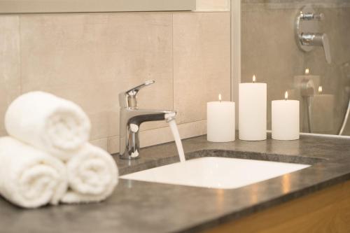 a bathroom sink with two white candles and towels at Alpinliving.Tirol in Aschau