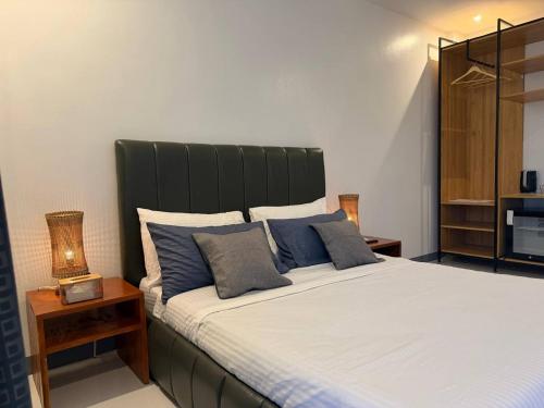 a bedroom with a large bed with blue pillows at Apples&Pears Hotel in Manaoag