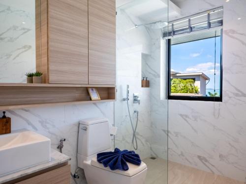 a bathroom with a toilet and a glass shower at Luxe 4BR Sunset Seaview Villa Private Infinity in Plai Laem