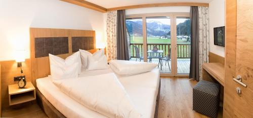 a bedroom with a large white bed and a balcony at Alpinliving.Tirol in Aschau