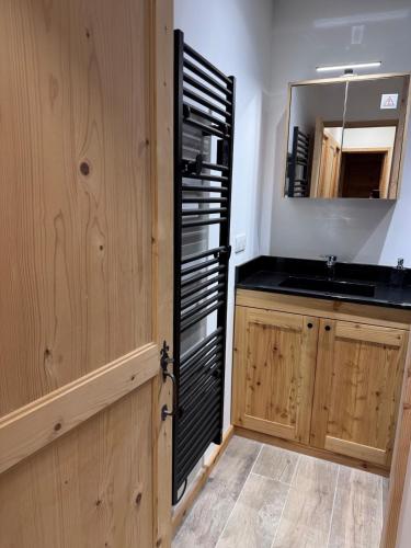 a kitchen with a sink and a black refrigerator at Les Racines Chalet in Villard-Reculas