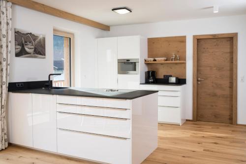 a kitchen with white cabinets and a black counter top at Alpinliving.Tirol in Aschau
