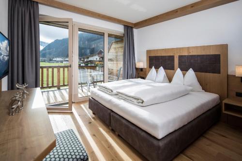 ein Schlafzimmer mit einem großen Bett und einem großen Fenster in der Unterkunft Alpinliving.Tirol in Aschau