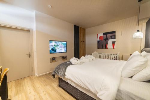 a bedroom with a large white bed and a tv at Omega Suites 31 in Tríkala