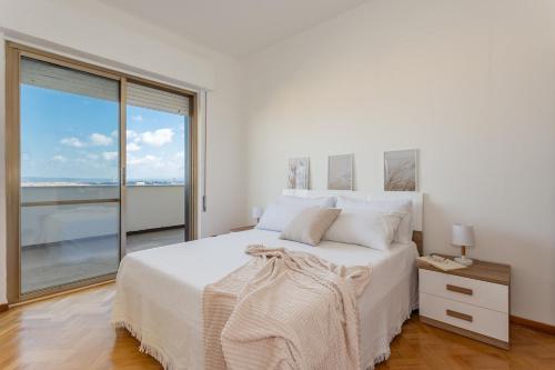 a white bedroom with a large bed and a large window at Penthouse Magic View - Large penthouse in the center in Oristano
