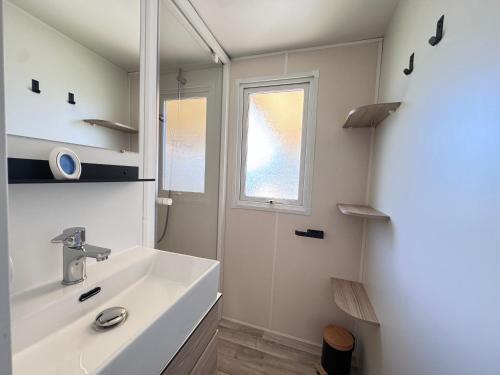 a white bathroom with a sink and a window at casa Laetitia in Lège-Cap-Ferret