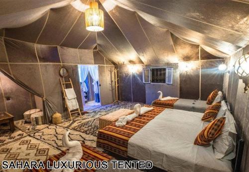 a room with two beds in a tent at Sahara Luxurious Tented in Merzouga