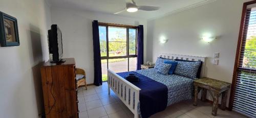 a bedroom with a bed and a tv and a window at Spacious - Sunrise over the sea in Urangan