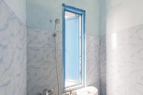 a bathroom with a shower with a toilet and a window at RedDoorz at Arca Hostel Lampung in Lampung