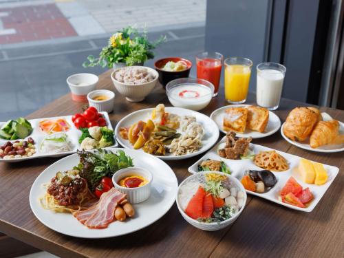 a wooden table with plates of food and drinks at Susukino Granbell Hotel in Sapporo
