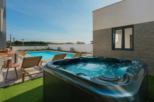 a hot tub on a lawn next to a swimming pool at Chill Villa - Signature by Paradise Portugal in Mariquiteira