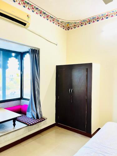 a bedroom with a black cabinet and a window at Lotus hotel in Nāthdwāra
