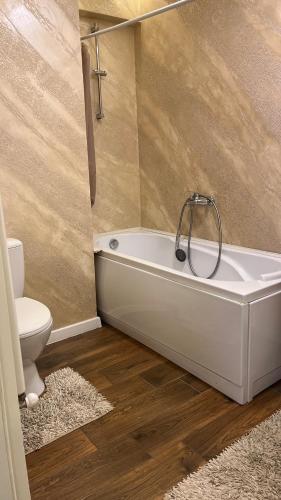 a bathroom with a white tub and a toilet at ZBI Apartament in Oradea