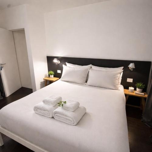 a bedroom with a white bed with towels on it at R Platano House in Como