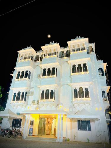 a large white building with lights on it at night at Lotus hotel in Nāthdwāra