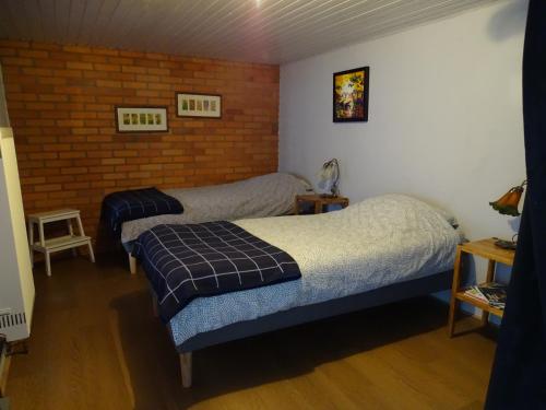 a bedroom with two beds and a brick wall at B&B Piccardie in Emlichheim