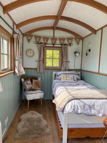 a bedroom with a bed and a window at Shepherds Huts Tansy & Ethel in rural Sussex in Arundel