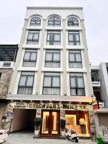 a large white building with windows and a scooter parked in front at X-Men Hotel Thanh Hoa - Not Near Sam Son Beach in Thanh Hóa