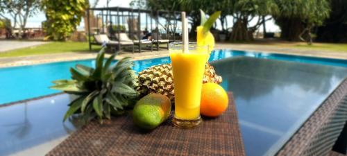 a drink and fruit on a table next to a pool at Retraite soleil sérénité in Pamunugama