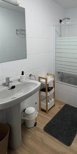 a bathroom with a sink and a mirror and a tub at Apartamento Cabo de Ajo in Ajo