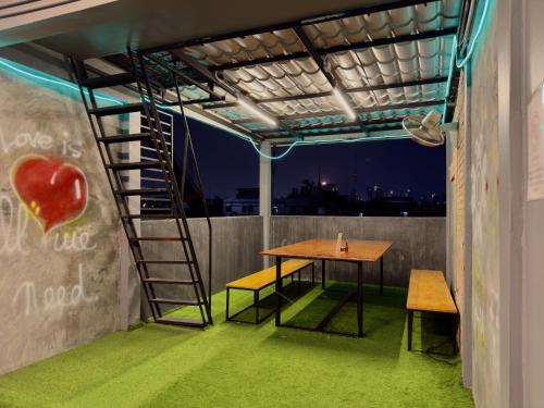 a room with a table and a ladder on a roof at Nomad Yard Hostel in Bangkok