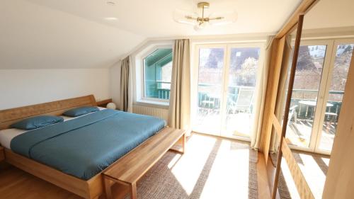 a bedroom with a bed with blue sheets and windows at Vienna Woods Residence in Gaaden
