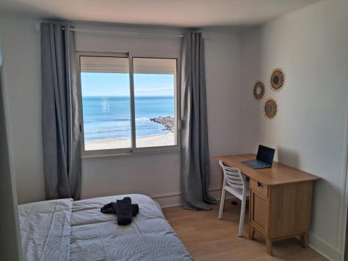 a bedroom with a bed and a desk with a laptop at Horizon Bleu Duplex 2 chambres vue mer in Palavas-les-Flots