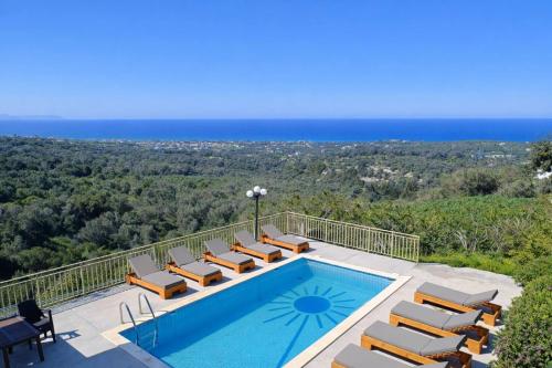 a swimming pool with lounge chairs and the ocean at Great Escape Sea View Private Pools, Jacuzzi & Ultimate Relaxation in Maroulás