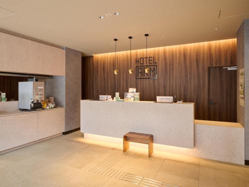 a hotel lobby with a counter and a stool at Hotel ARM ObihiroEkimae in Obihiro
