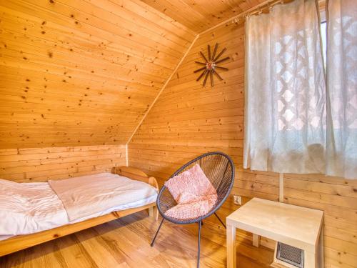 a room with a bed and a chair in a wooden room at Domek ANITA in Polańczyk