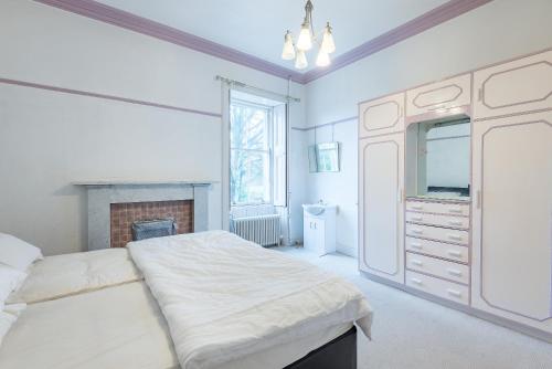 a white bedroom with a large bed and a fireplace at OYO Ashlea Manor in Monifieth