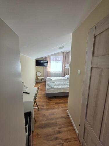 ein Schlafzimmer mit einem Bett, einem Schreibtisch und einer Tür in der Unterkunft W Dolinie in Działdowo