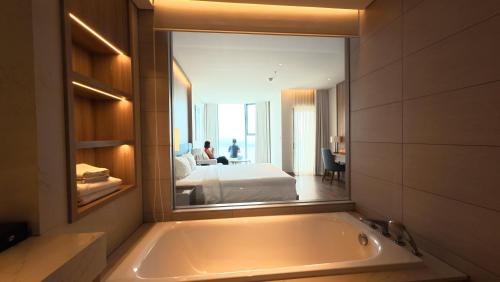 a bathroom with a bath tub and a bedroom at A LA CARTE Hạ Long Bay View biển tầng cao in Ha Long