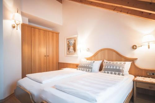 a bedroom with a large bed with white sheets and pillows at Arthotel Gratschwirt in Dobbiaco