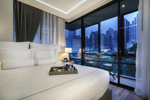 a bedroom with a large white bed and a large window at Tastoria Collection Sukhumvit in Bangkok