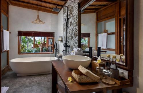 a bathroom with a large tub and a large sink at Berlima Boutique Resort in Ubud