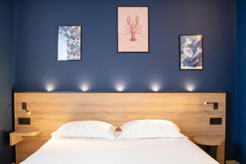 a bedroom with a large bed with a blue wall at Brit Hotel Saint Malo – Le Transat in Saint Malo