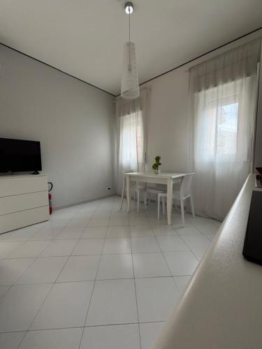 a white living room with a table and a tv at Rael in Cefalù