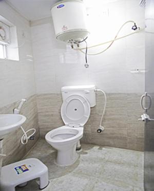 a bathroom with a white toilet and a sink at Leo Stays in Bangalore