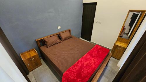 a small bedroom with a bed with a red blanket at Moms homestay 3 Bedrooms in Vagamon