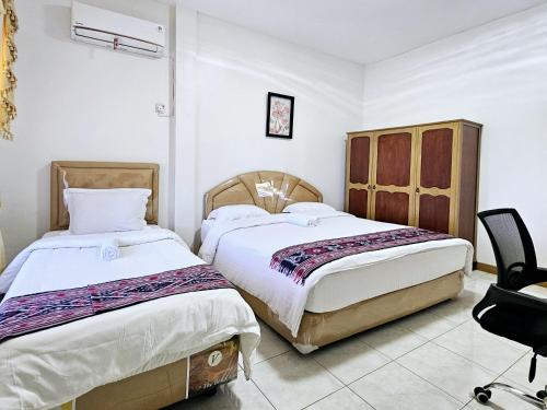 a bedroom with two beds and a chair at Flamboyan House in Padang